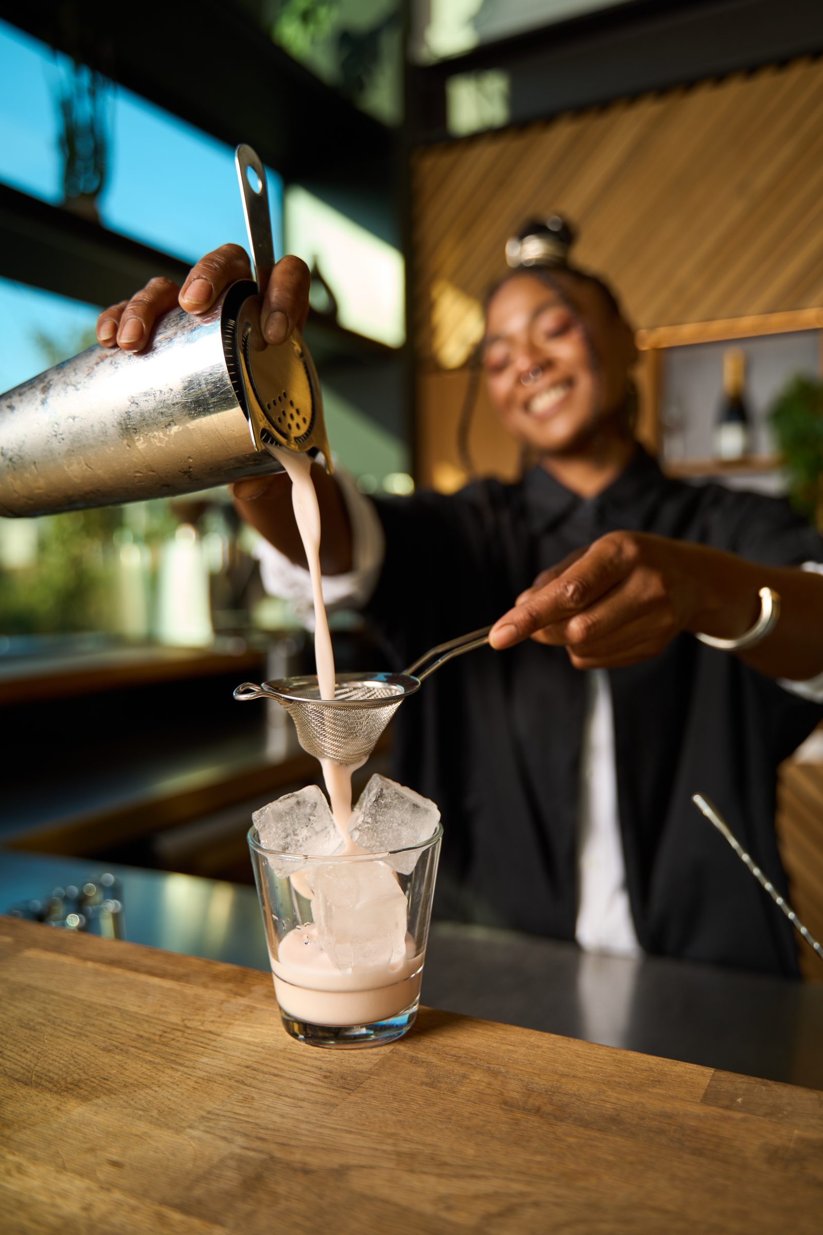 Bartender straining a cocktail into a glass